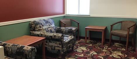 A room with a patterned carpet, a sofa, two chairs, and a small table.