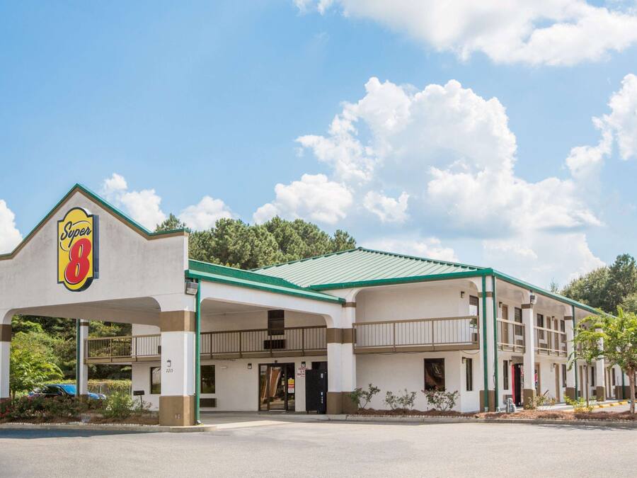 Un motel Super 8 con techo verde, varios balcones y un estacionamiento.