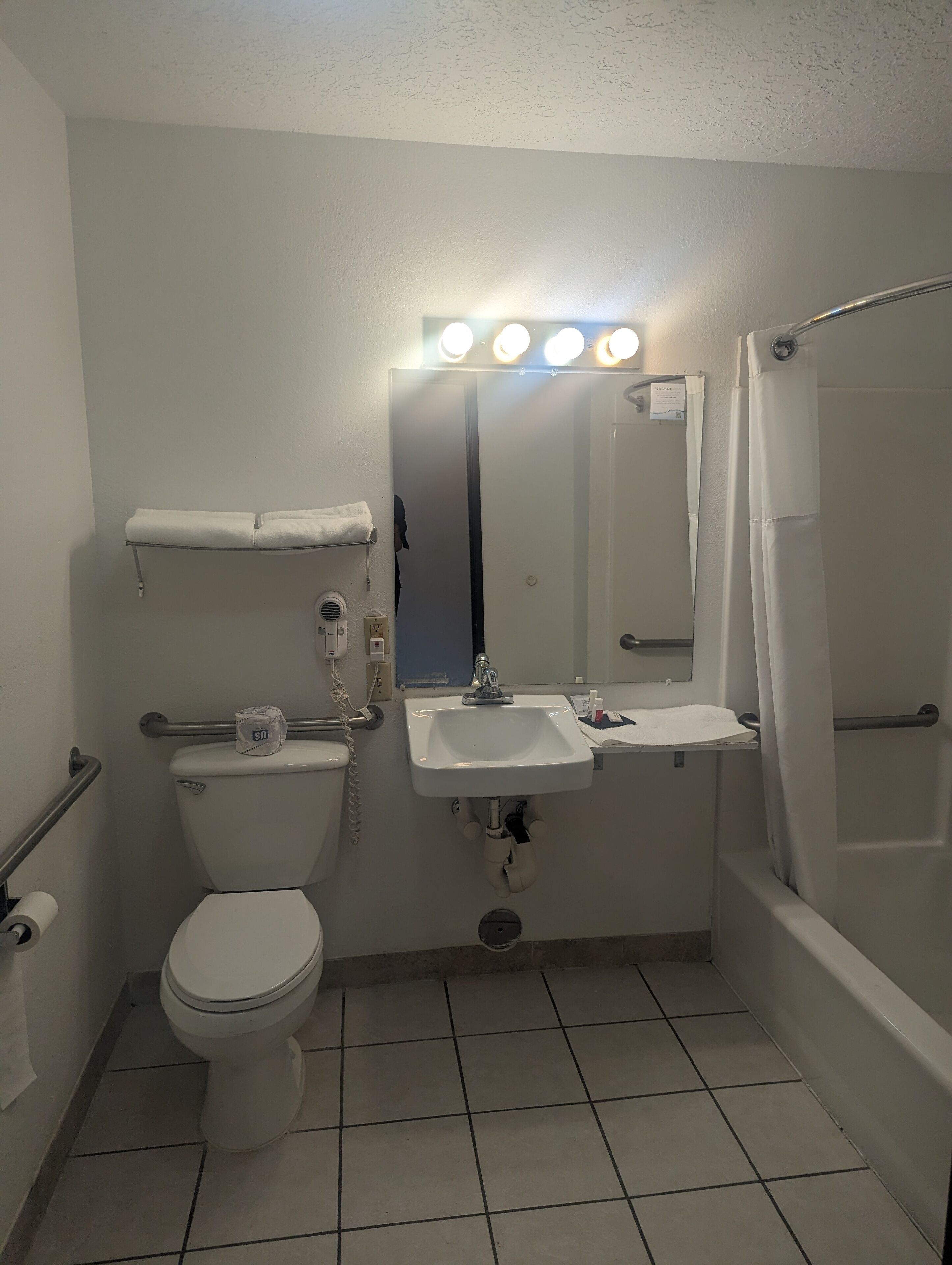 A bathroom with a toilet, sink, mirror, and shower.