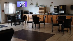 A kitchen with a TV, wooden cabinets, a coffee machine, and a refrigerator. - Super 8 by Wyndham Price (Price)