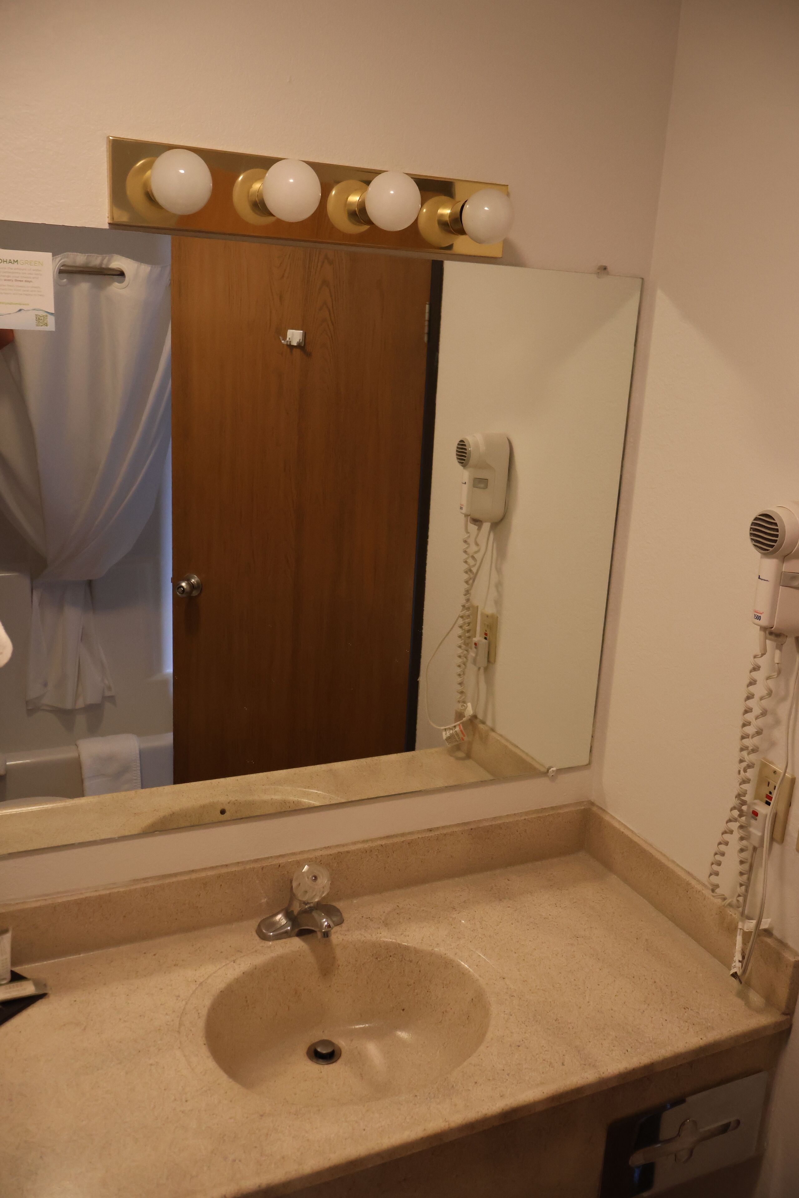 Un baño con lavabo, espejo, secador de pelo y toallero.