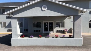 A building with a grey facade, a central entrance with double doors, and a small porch area with flower planters. - Super 8 by Wyndham Price (Price)
