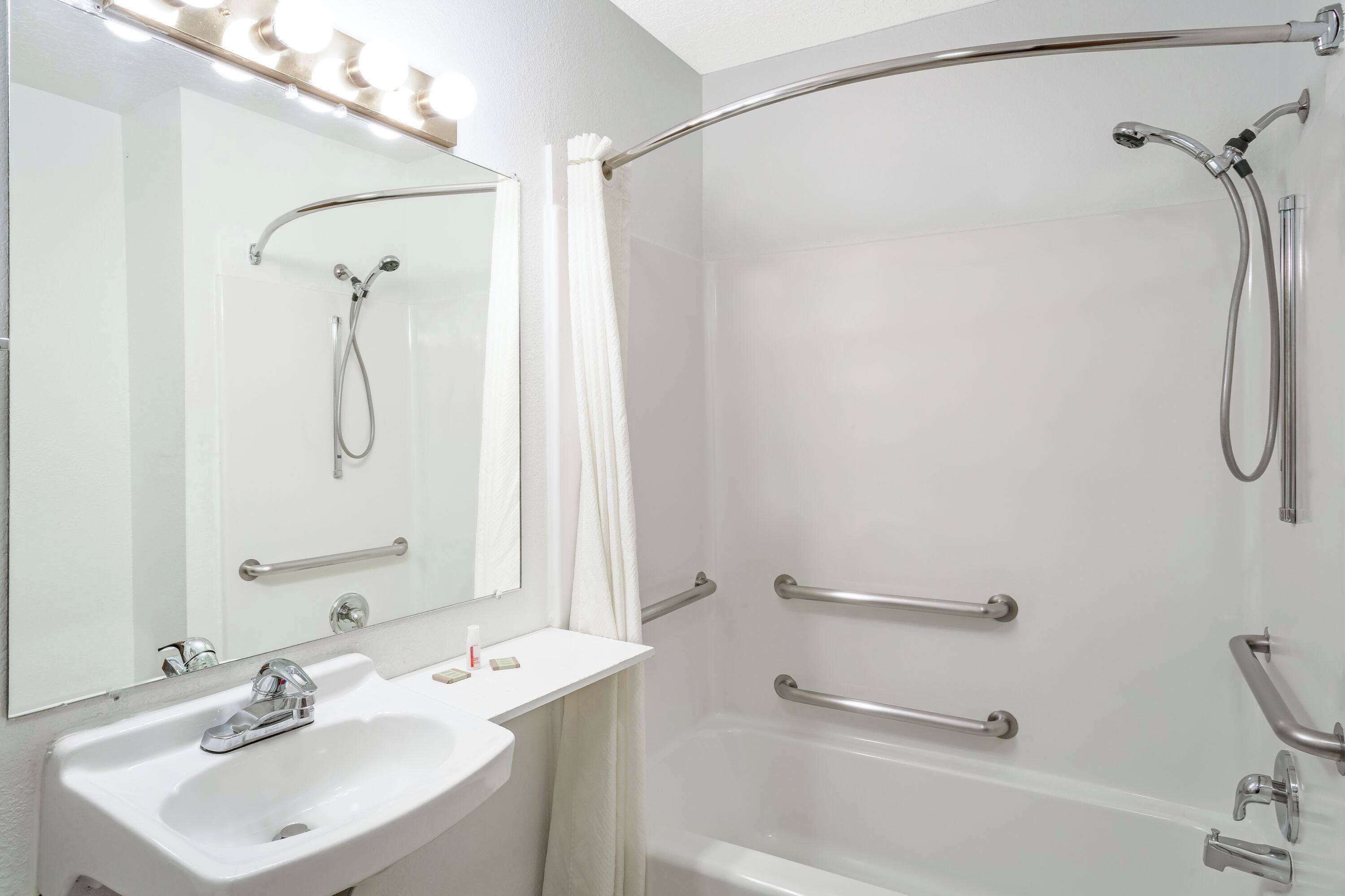 A modern bathroom with a white sink, mirror, and shower.