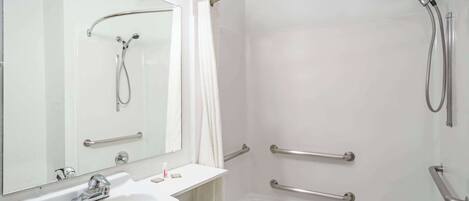 A modern bathroom with a white sink, mirror, and shower.