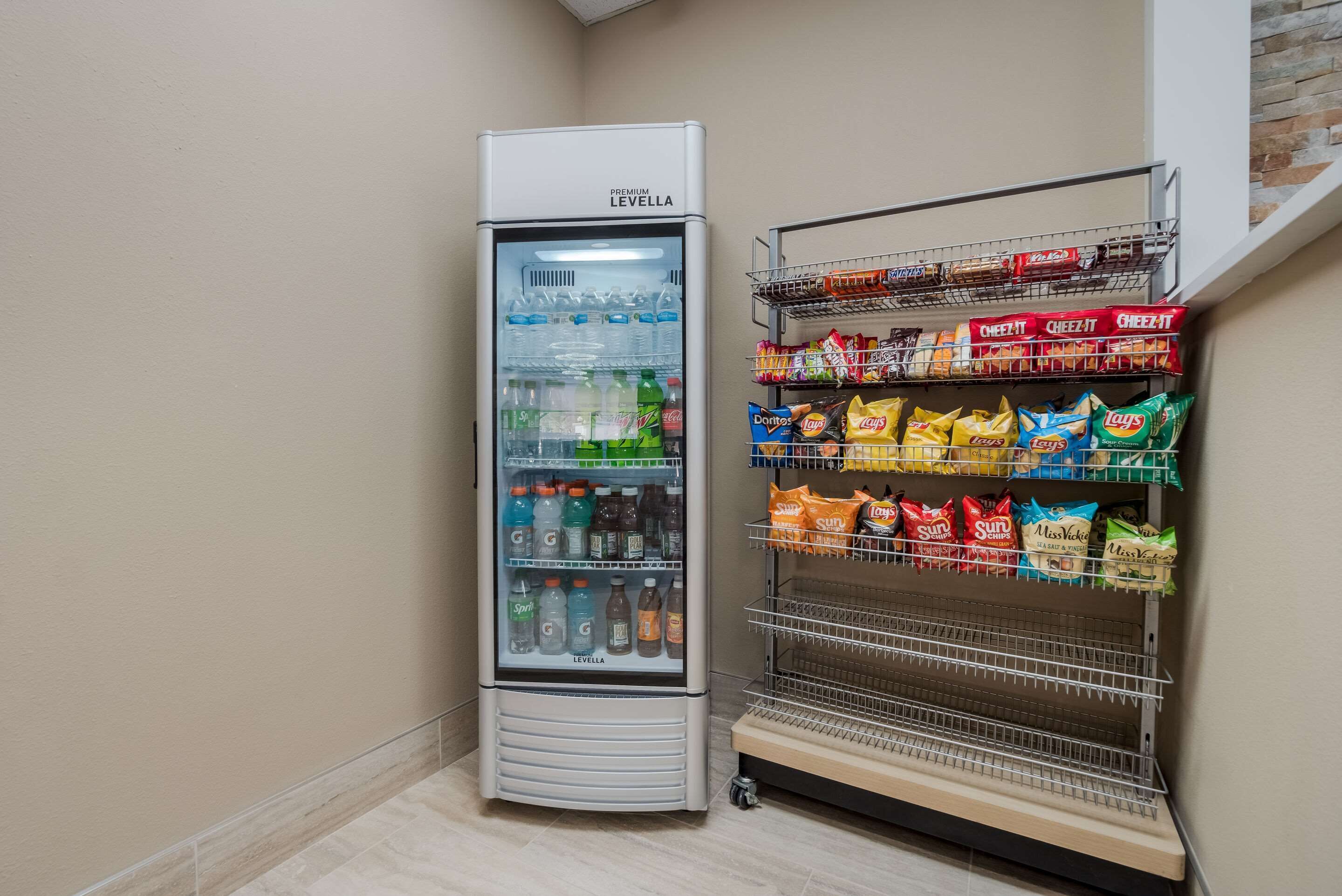 Een gekoelde vitrine gevuld met drankjes en een plank met verschillende chips en snacks.