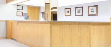 A reception area with a wooden counter, framed certificates on the wall, and a tiled floor.