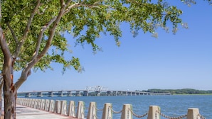 A waterfront promenade with a paved walkway, a chain barrier, and a bridge in the background. - Super 8 by Wyndham Port Royal/Beaufort (Port Royal)