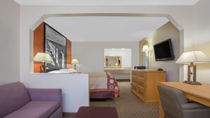A hotel room with a bed, a desk, a chair, a sofa, a television, and a mirror. - Super 8 by Wyndham Port Royal/Beaufort (Port Royal)
