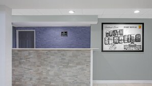 A reception area with a blue textured wall, a grey stone wall, and a framed welcome sign. - Super 8 by Wyndham Port Royal/Beaufort (Port Royal)