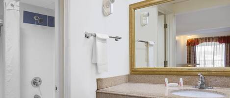 A bathroom with a sink, mirror, towel rack, and shower.