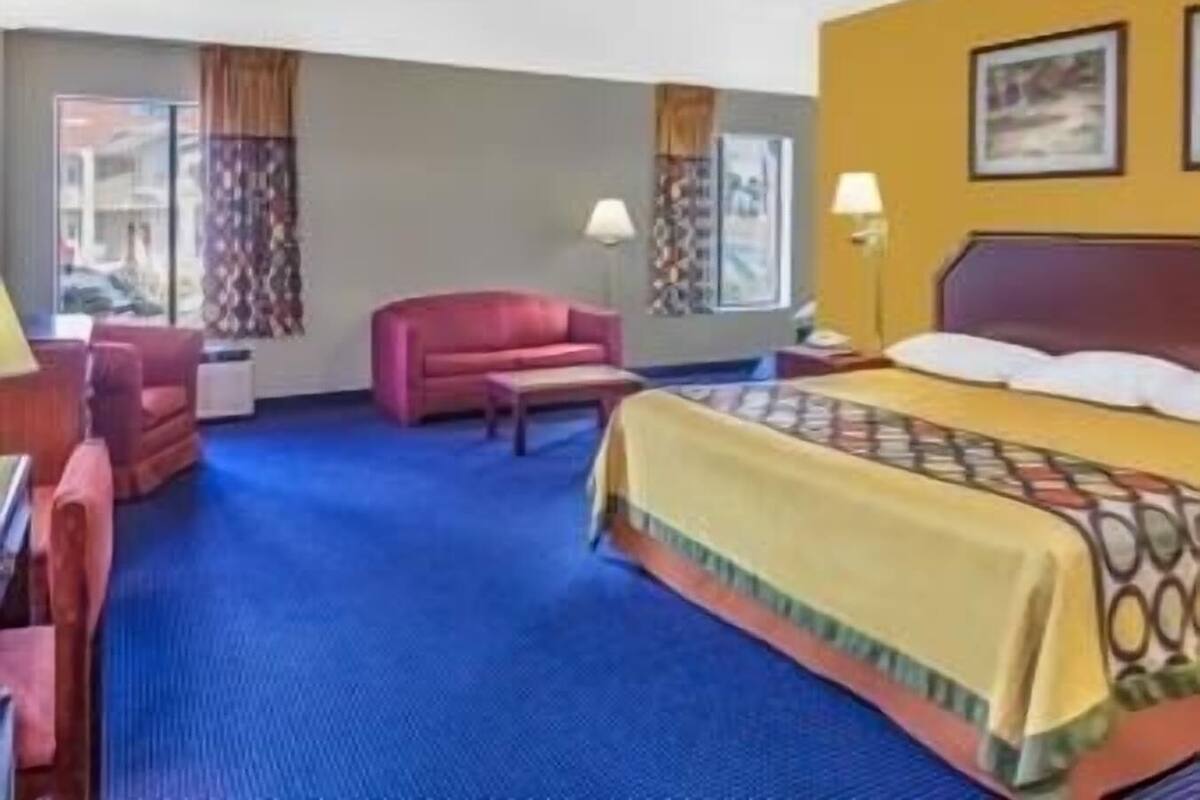 Una habitación de hotel con cama, escritorio, silla y sofá.
