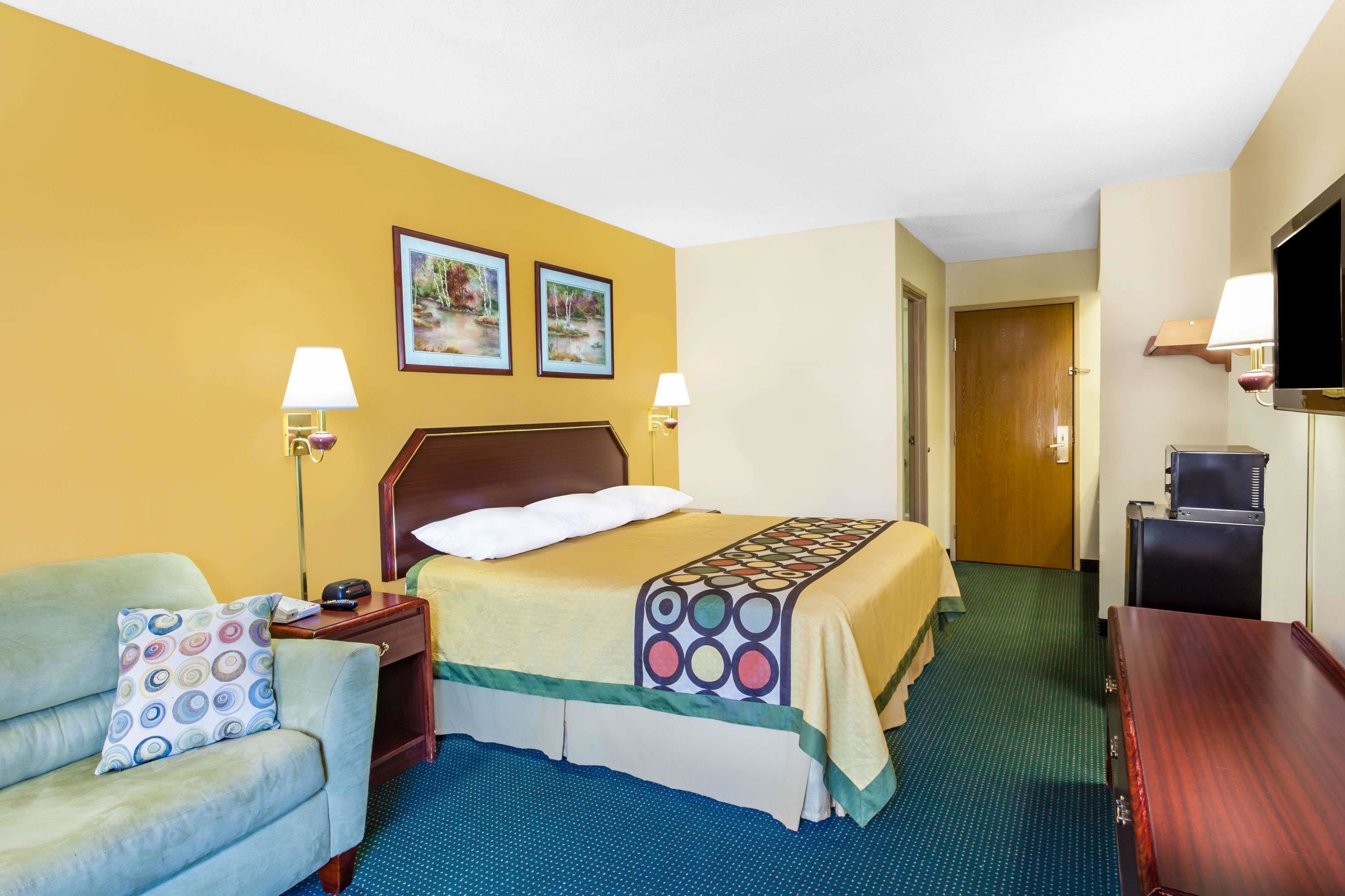 A hotel room with a bed, a sofa, a desk, and a TV.