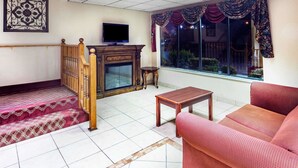 Una sala de estar con un sofá, una mesa de madera, un televisor y una chimenea.
