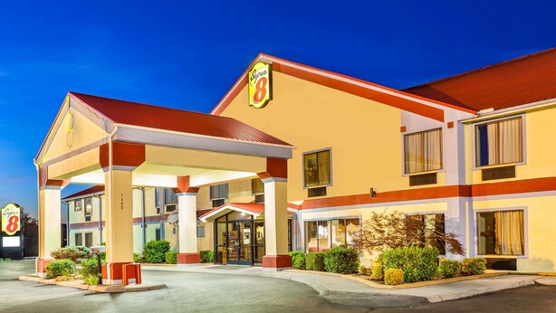 Hotel con fachada roja y color crema, un acceso cubierto y un letrero con el número 8.