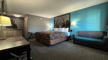 A hotel room with a bed, a desk, a chair, a sofa, and a large mirror.