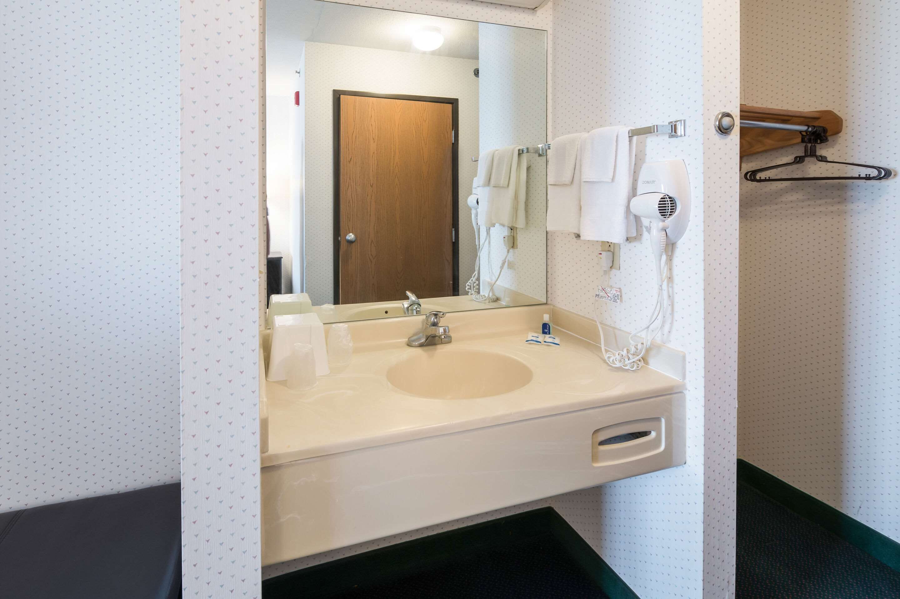 A bathroom with a sink, mirror, and towel rack.