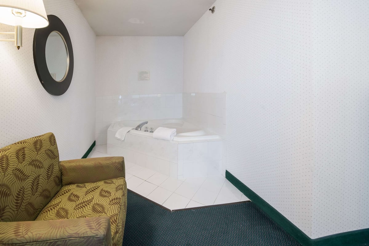 A bathroom with a bathtub, a toilet, and a patterned sofa.