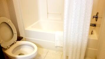 A bathroom with a toilet, a bathtub, and a shower curtain.