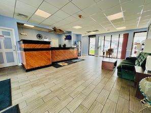 A reception area with a wooden reception desk, a clock, and a ceiling fan.