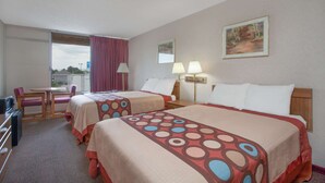 A hotel room with two beds, a desk, and a chair.