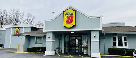 A Super 8 motel with a prominent yellow and red sign, a parking lot, and a simple, functional building design.