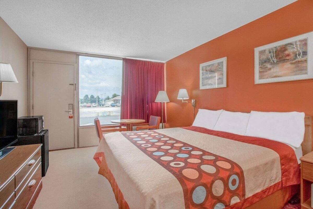A hotel room with a bed, a desk, a chair, a TV, and a window with a view.