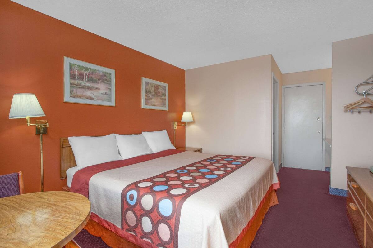 A hotel room with a large bed, two bedside lamps, a wooden table, and a door.