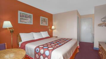 A hotel room with a large bed, two bedside lamps, a wooden table, and a door.