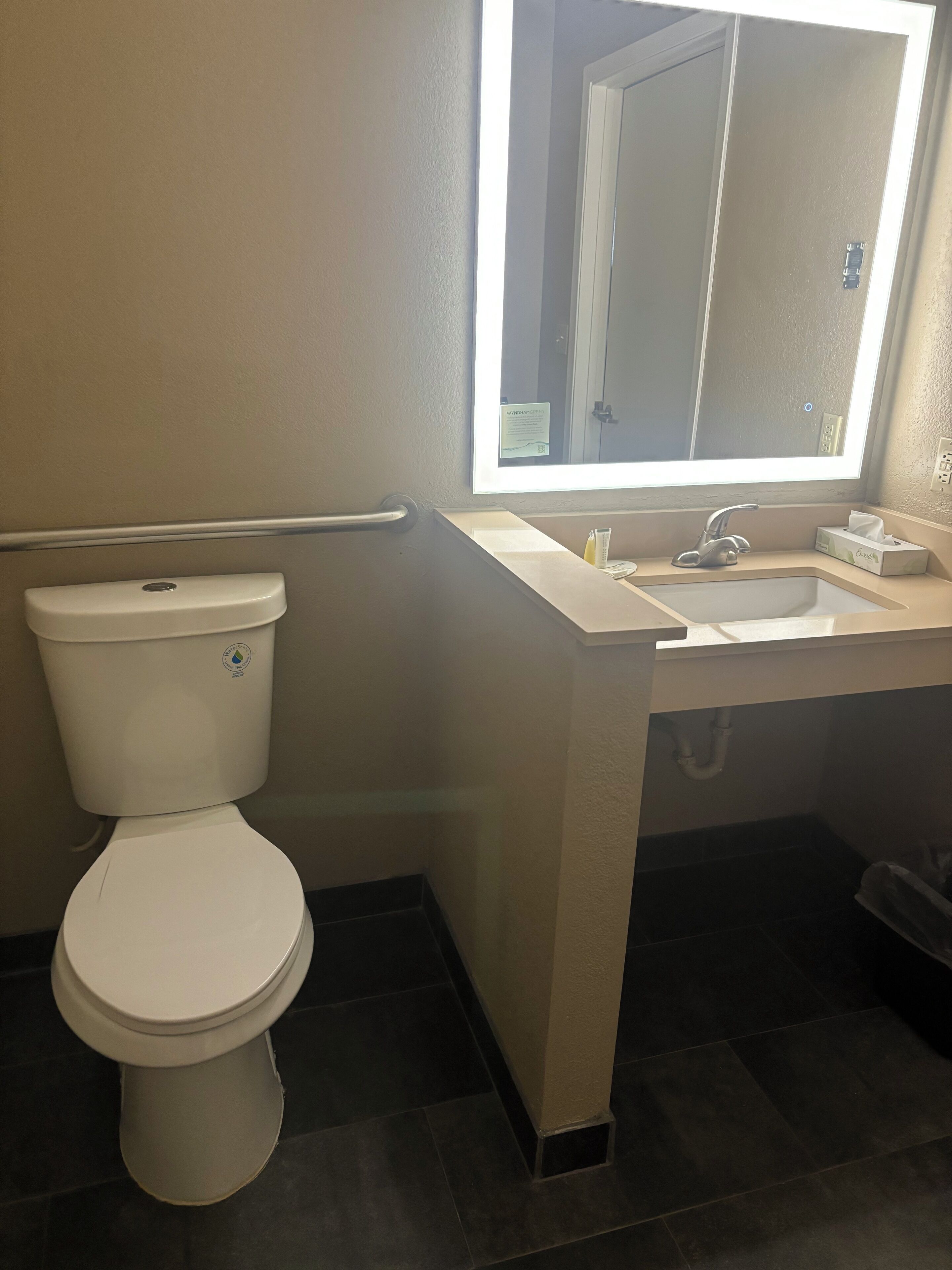 Une salle de bain avec des toilettes, un lavabo et un miroir.