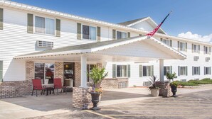Un motel con entrada cubierta, mesas al aire libre y un asta de bandera.