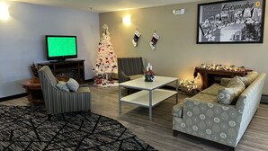 Una sala de estar con una televisión, un árbol de Navidad, un sofá, una mesa de centro y un cuadro en la pared.