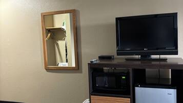A hotel room with a bed, a television, a microwave, and a refrigerator.