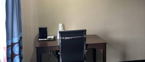 Habitación de hotel con cama, escritorio, silla, cafetera y calefacción.