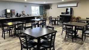 Un restaurante con varias mesas y sillas, una barra con dispensador de bebidas y un televisor montado en la pared.