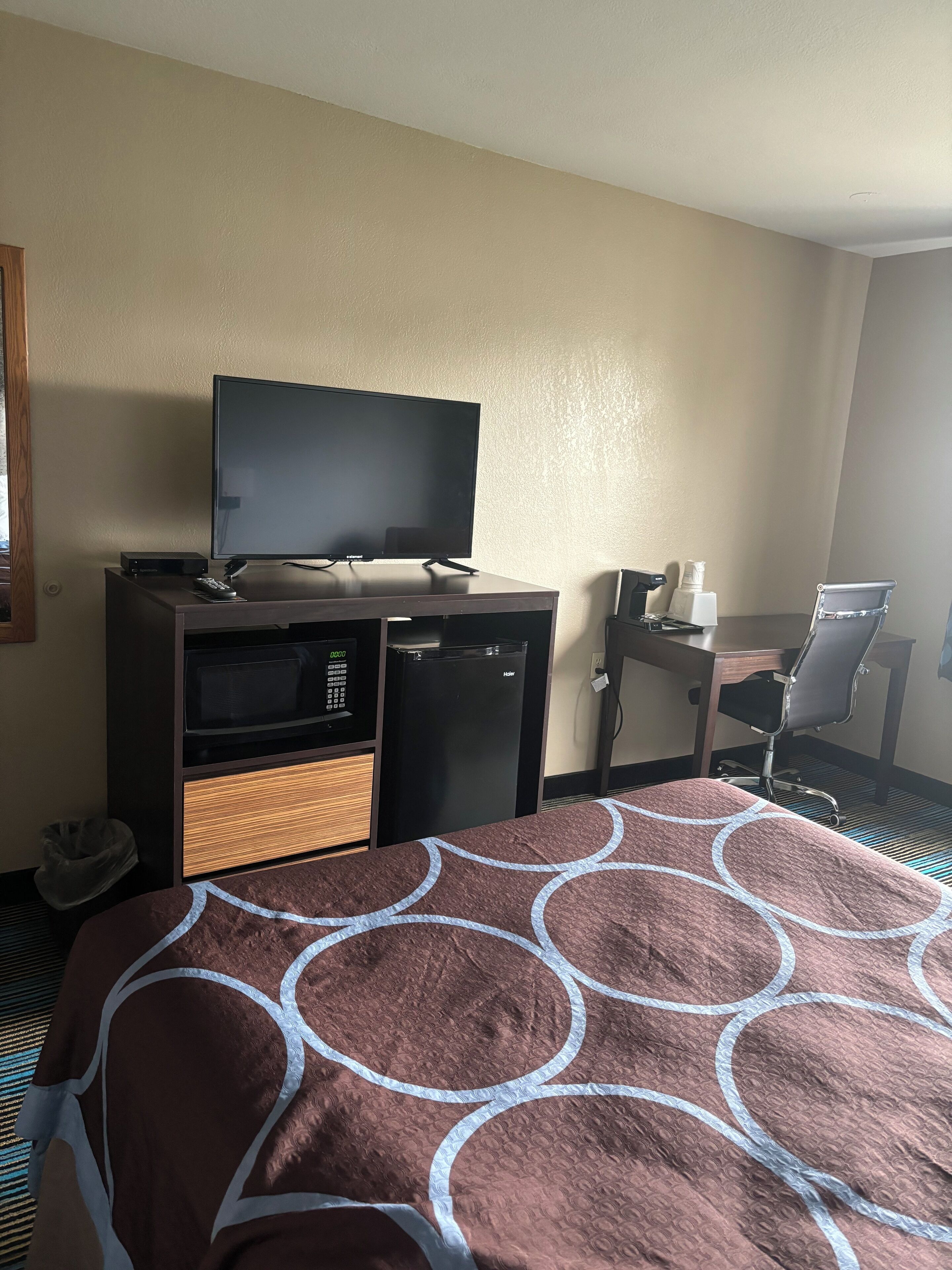 Une chambre d’hôtel équipée d’un lit, d’un bureau, d’une télévision, d’un réfrigérateur et d’une chaise.