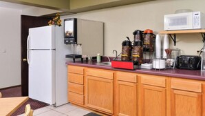 Una cocina compacta equipada con refrigerador, cafetera, microondas y tostadora.