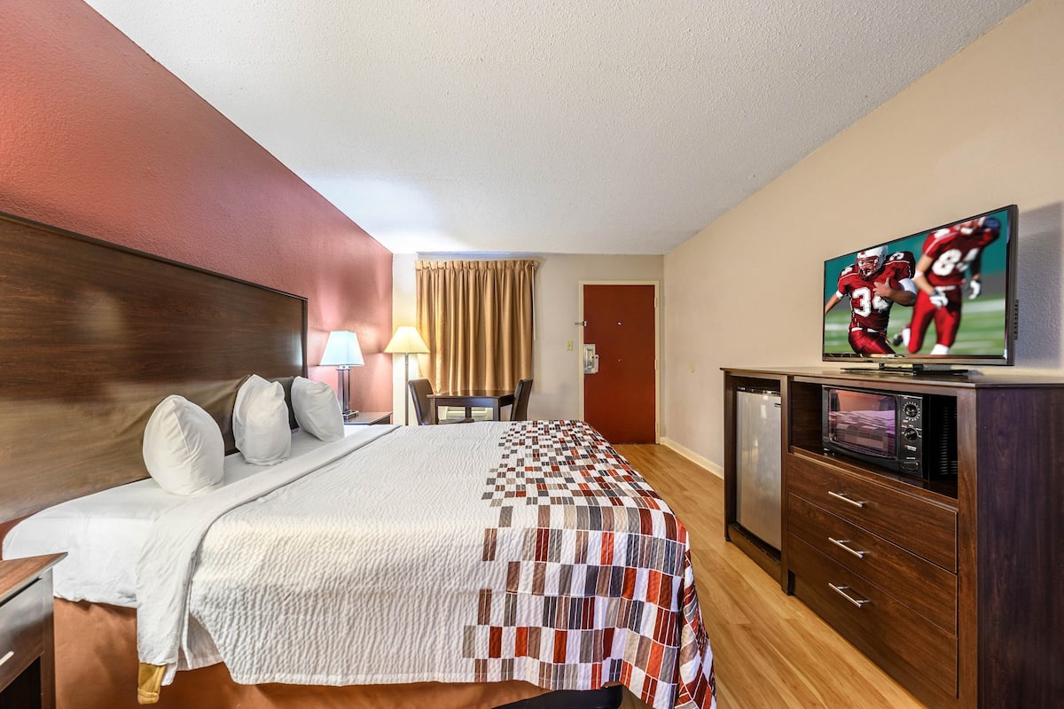 A hotel room with a bed, a TV, a microwave, and a small desk.