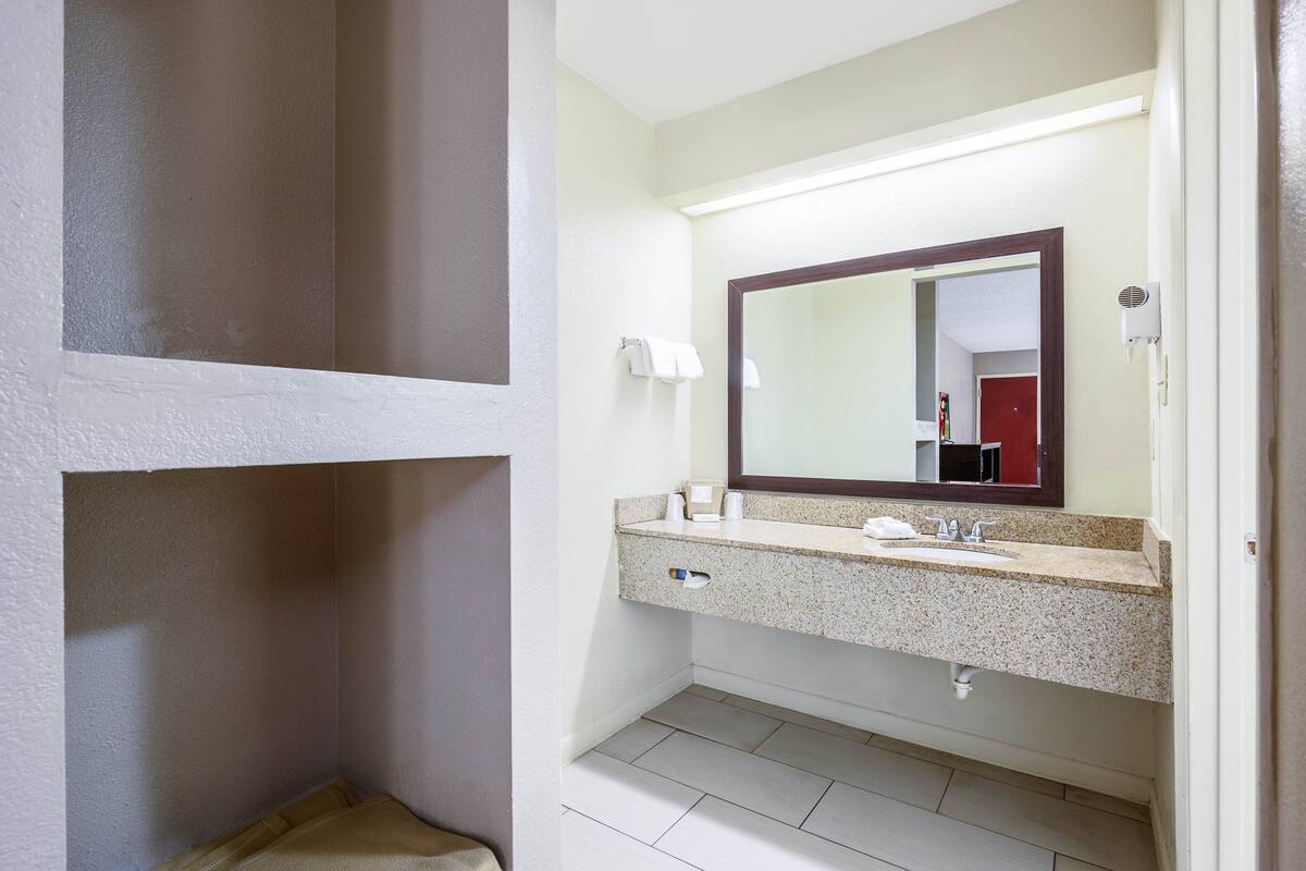 A bathroom with a granite countertop, a mirror, a towel rack, and a toilet.