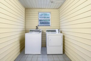 A laundry room with two stacked washers and dryers, a window, and a ceiling vent.