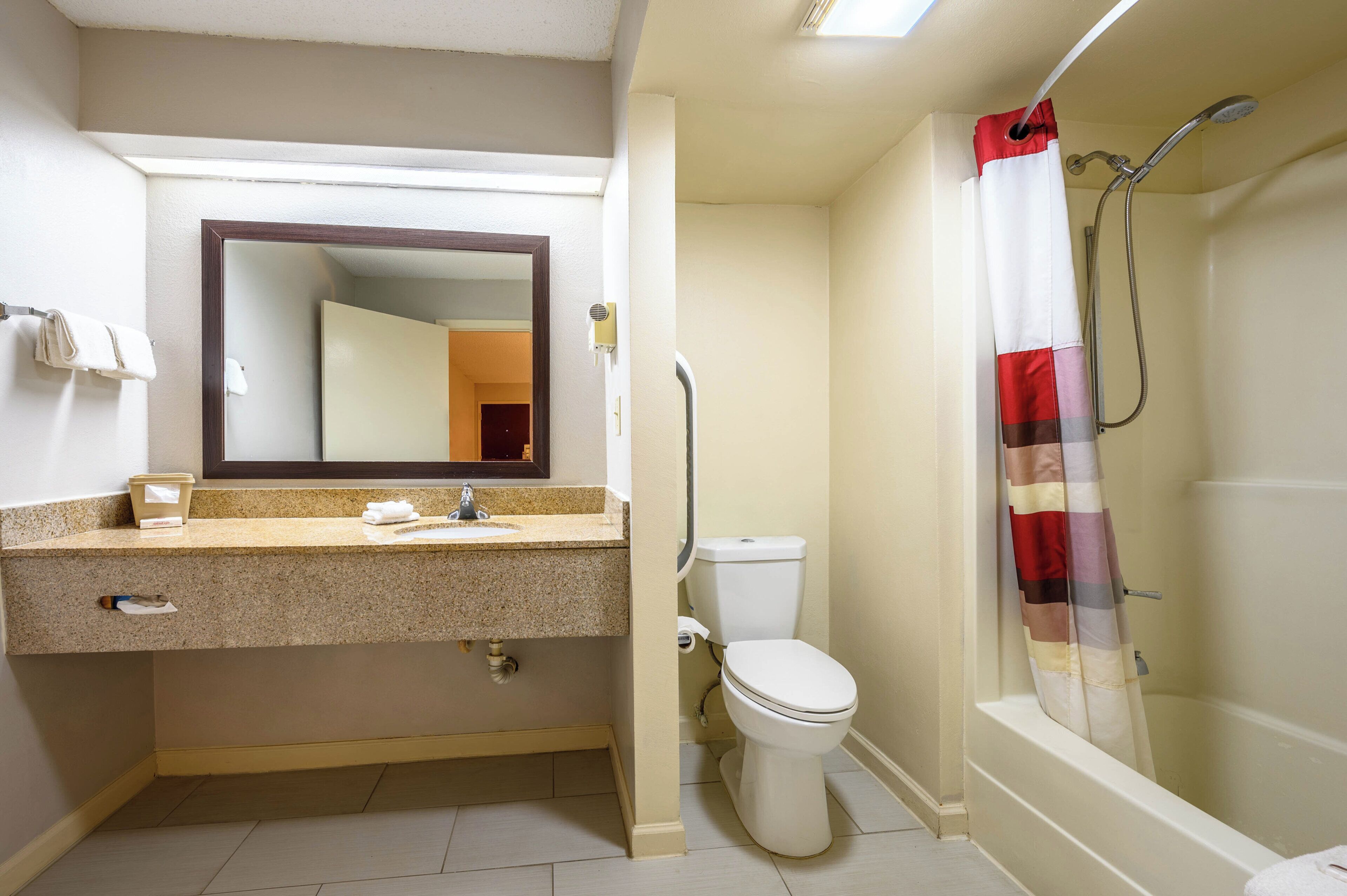 A bathroom with a sink, mirror, toilet, and shower.