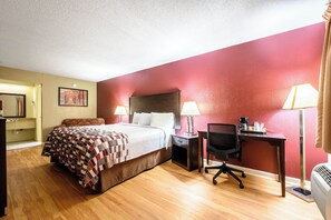 A hotel room with a bed, desk, chair, and a red accent wall. - Red Roof Inn Sylacauga (Sylacauga)