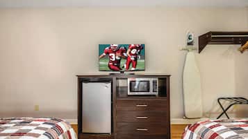 Een hotelkamer met een bed, een bureau met een televisie, een magnetron en een kleine koelkast.