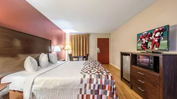 Una habitación de hotel con cama, televisión, escritorio y silla.