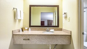 A bathroom with a granite countertop, a sink, a mirror, and a towel rack. - Red Roof Inn Sylacauga (Sylacauga)