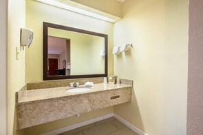 A bathroom with a granite countertop, a sink, a mirror, and a towel rack. - Red Roof Inn Sylacauga (Sylacauga)