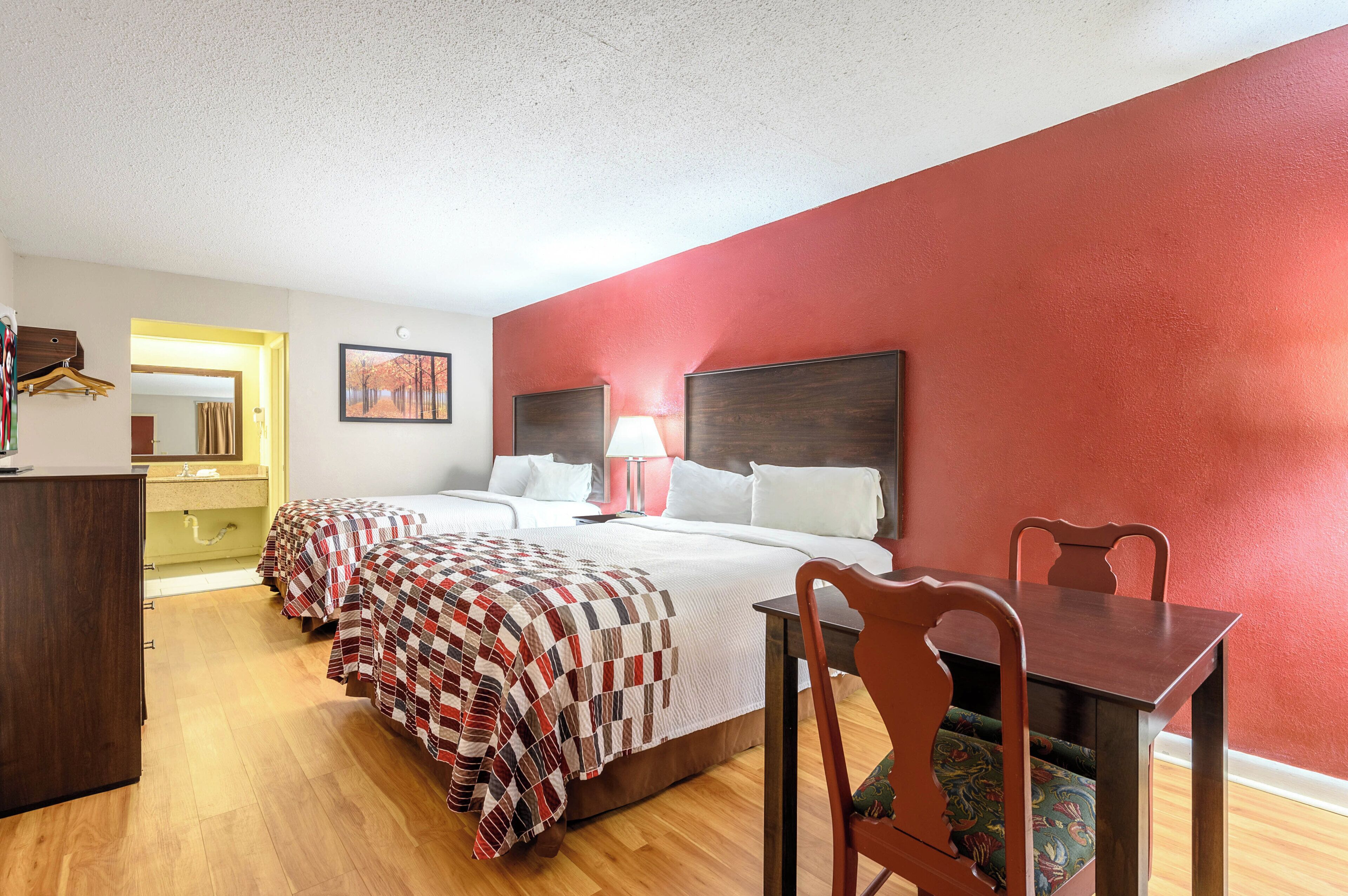 A hotel room with a large bed, two bedside tables, a desk, and a chair.