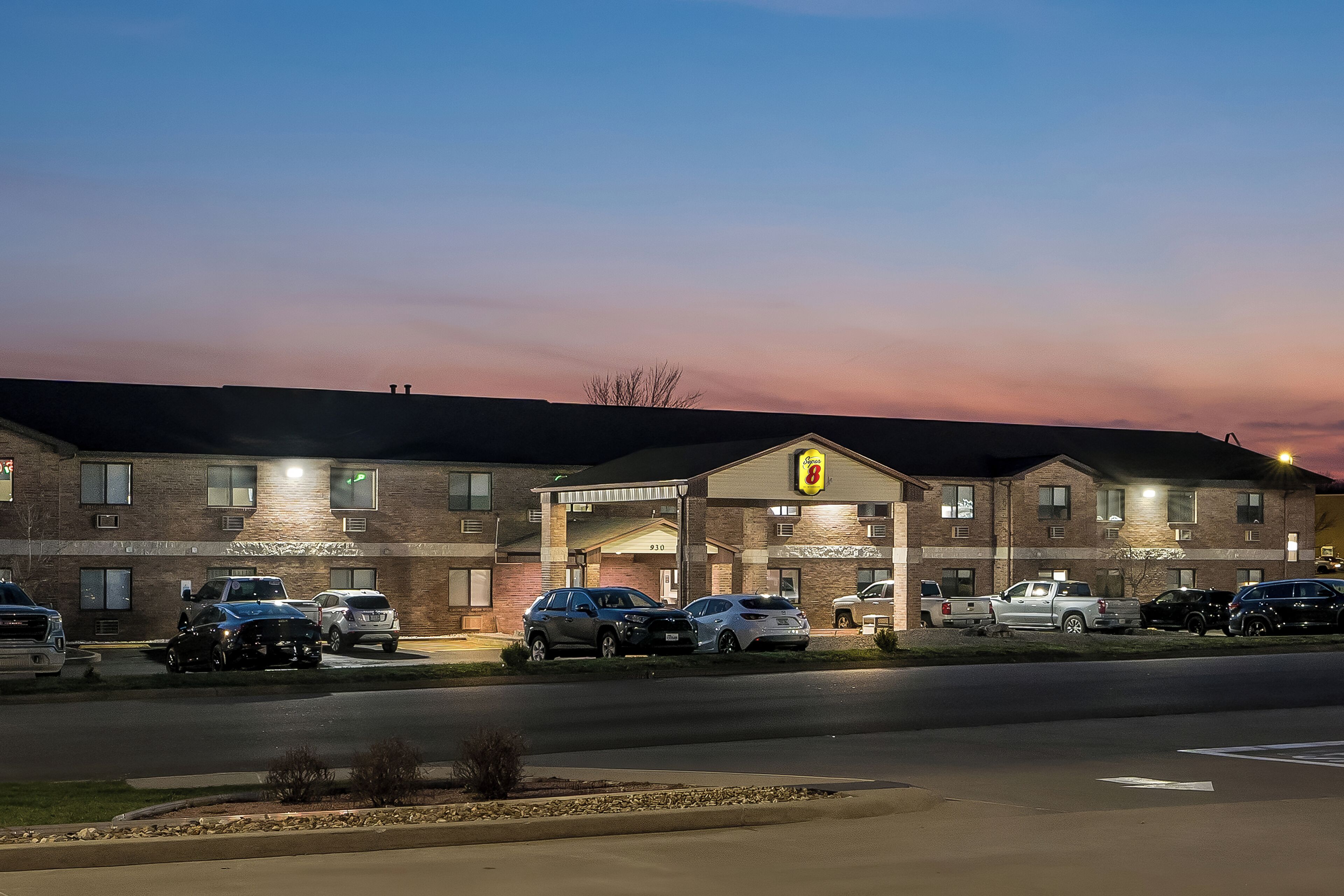 A motel with a brick facade, multiple parking spaces, and a sign indicating room number 910.