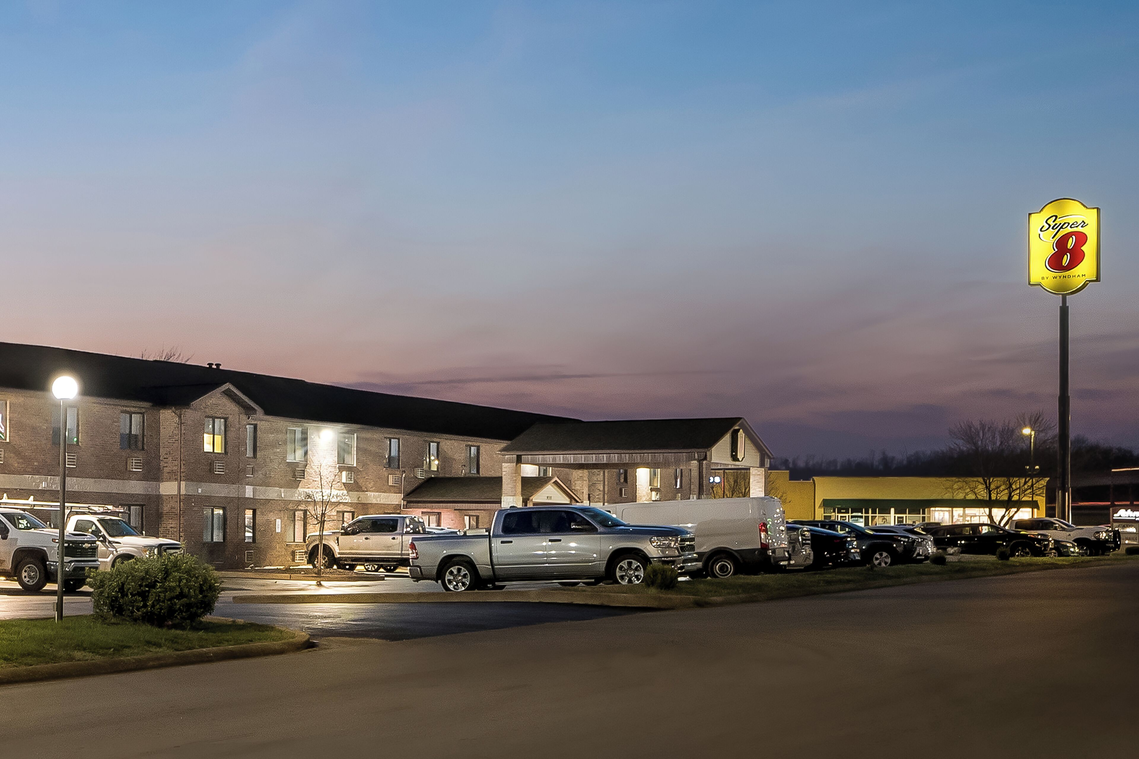 A parking lot with several vehicles, a brick building, and a sign that reads 'Super 8'.