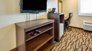 A hotel room with a flat-screen TV mounted on the wall, a wooden entertainment unit with remote controls, a coffee maker, and a patterned carpet. - Americas Best Value Inn Richmond San Francisco (Richmond)