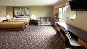 A hotel room with a bed, a sofa, a desk, and a TV.